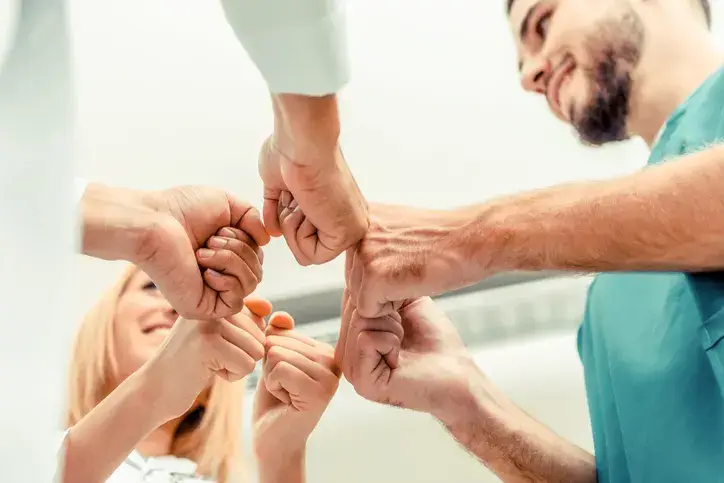 Doctor, surgeon and nurse join hands together.