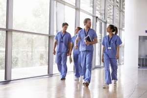 4 Ways to Spot a Traveler-Friendly Hospital Four healthcare workers in scrubs walking in corridor