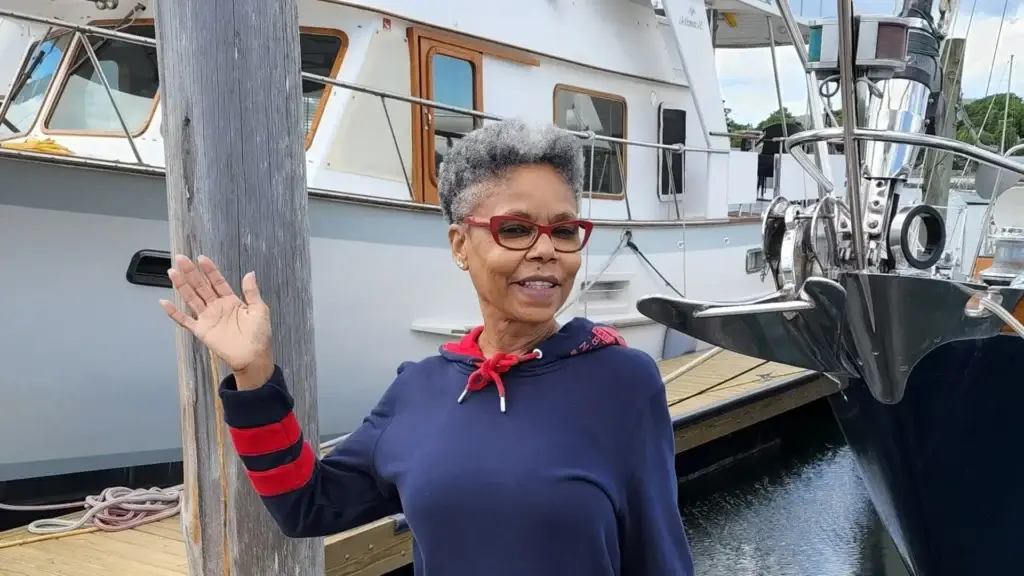 Debbie, a travel nurse, waving while standing in front of a boat