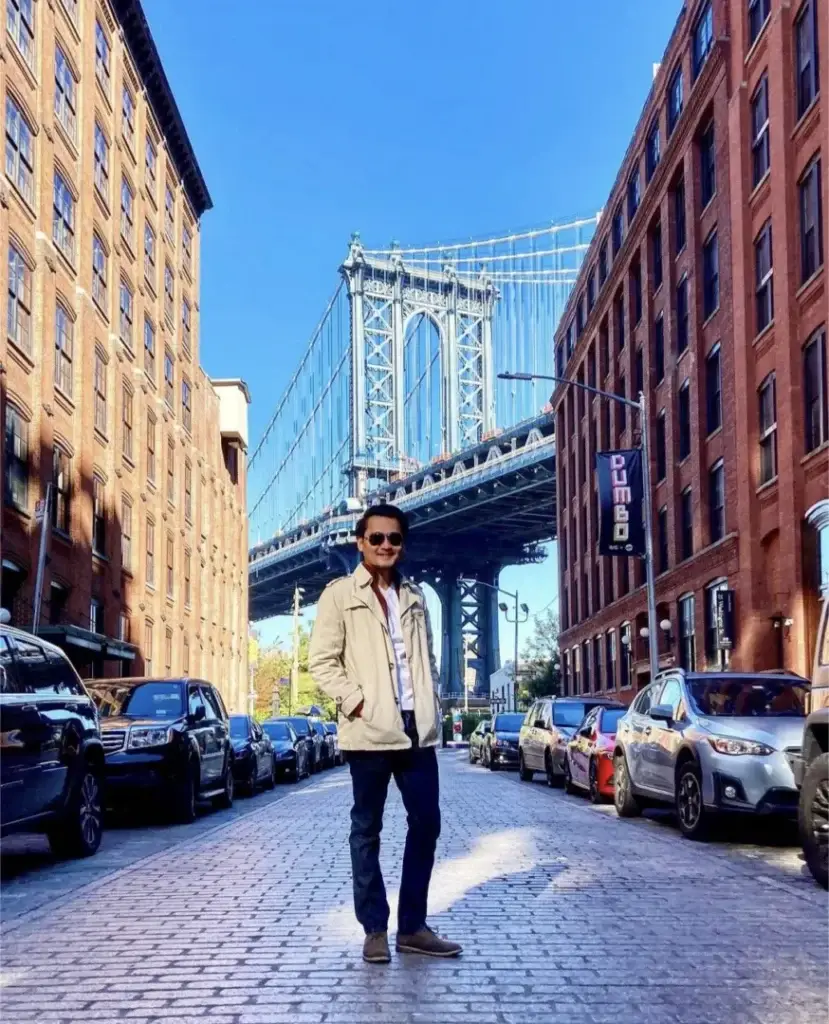 Raphael TNAA traveler standing in front of bridge in NYC
