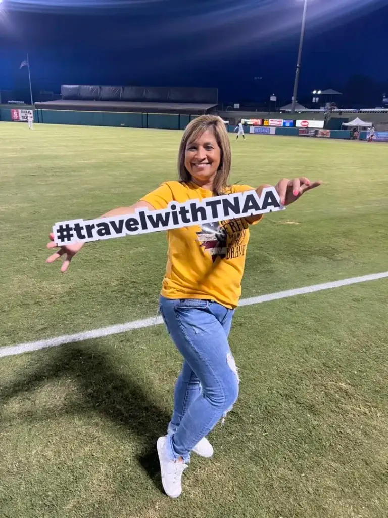 TNAA ambassador and travel nurse holding sign on baseball field