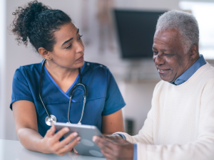 A healthcare professional using a tablet to interact with a patient in a hospital or clinical setting. A healthcare professional using a tablet to interact with a patient.