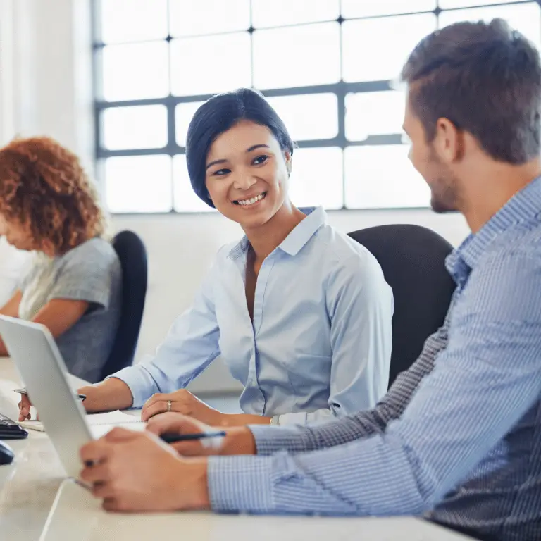 Healthcare professionals collaborating at laptops in a bright, modern office environment.