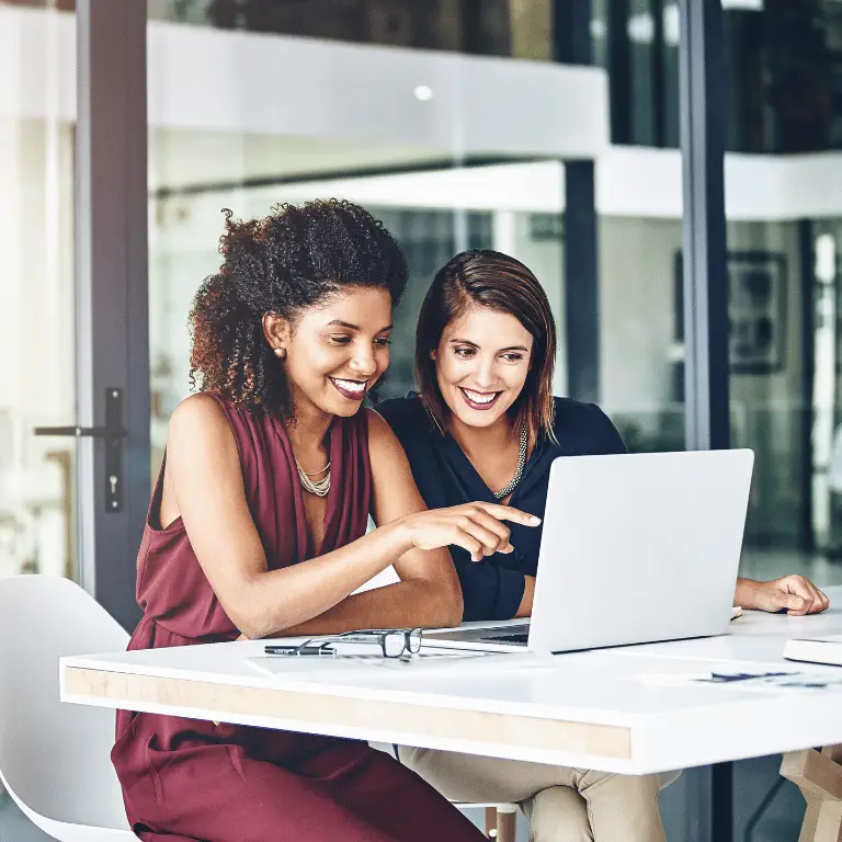 Two healthcare professionals collaborating on a laptop in a modern office setting.